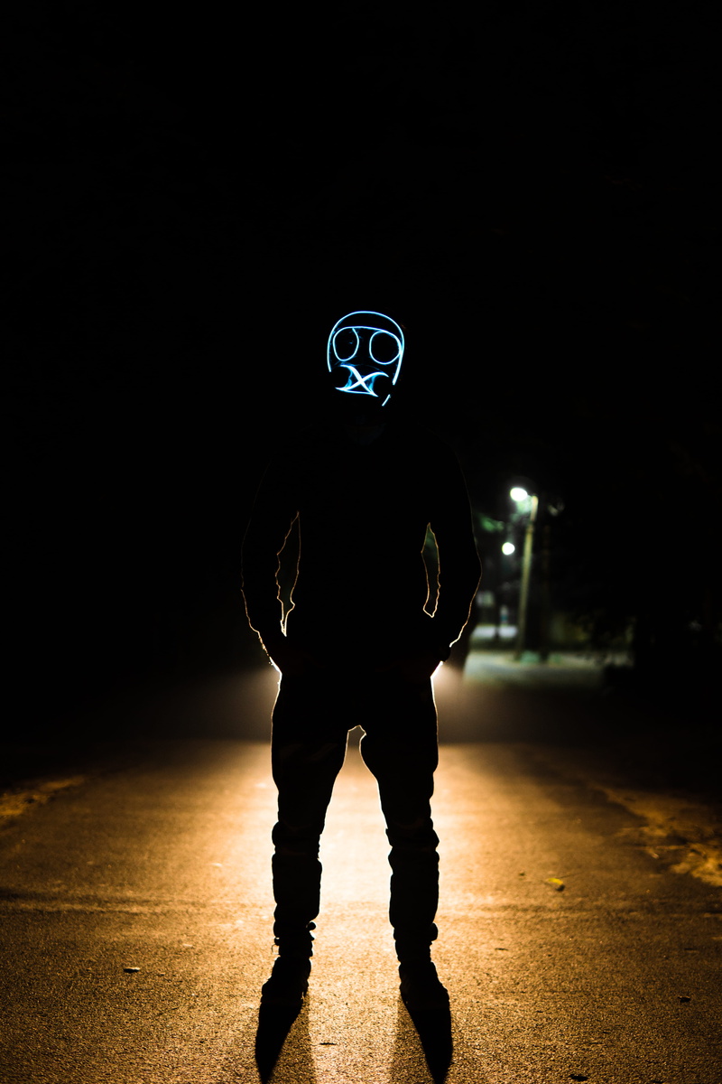 standing, disguise, casual clothing, lighting, person, dark, man, illuminated, hood, pedestrian, asphalt, front view, real people, sport, human, mask, silhouette