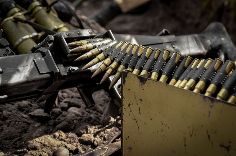 sunlight, outdoors, wheel, rifle, tape cartridges, MG-42, land vehicle, no people, black, still life, machinery, nature, close-up, field, transportation