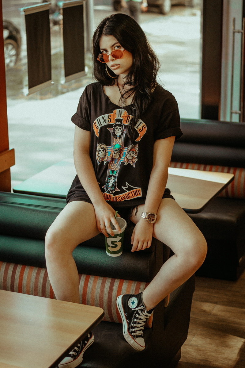 one person, leisure activity, sunglasses, hairstyle, couch, lifestyles, earring, sitting, room, young adult, adult, black, woman, three quarter length