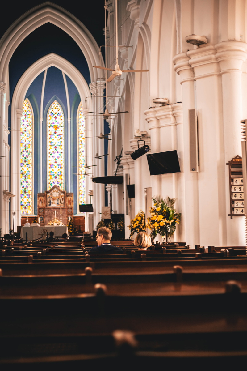 group of people, flower, church, indoors, blossom, aisle, place of worship, spirituality, building, architectural column, plant, divided, arch, built structure