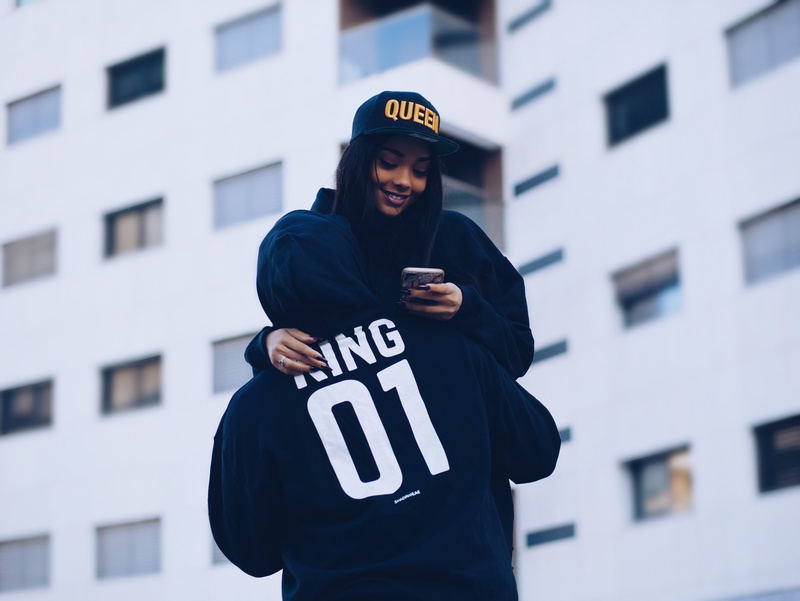 leisure activity, female, smartphone, mobile phone, rise, hat, wireless technology, young, city, clothing, text, one person, architecture, lifestyles, outdoors