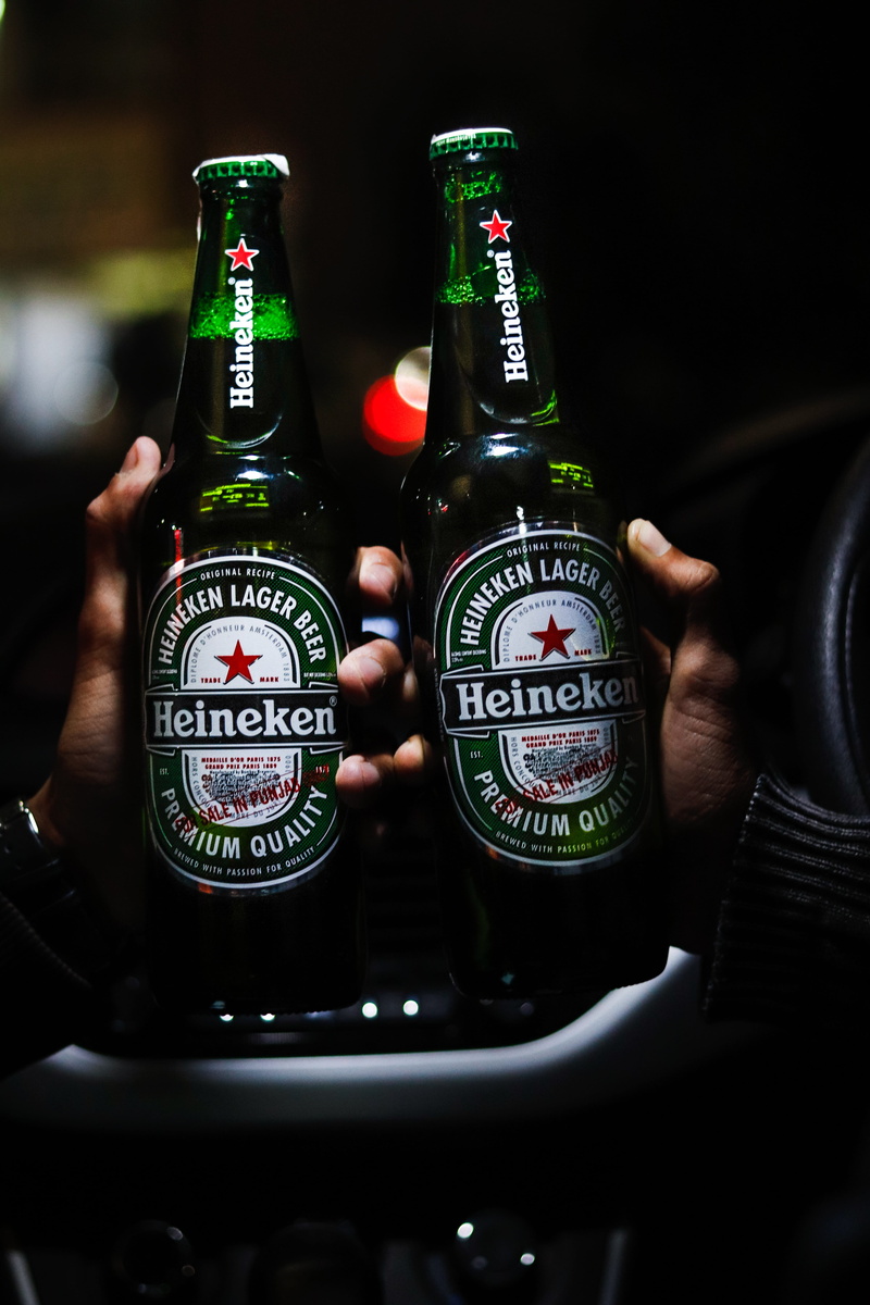 wine bottle, car, hand, beer bottle, human body part, red wine, container, beer, close-up, focus on foreground, beverages, indoors, finger, green, city