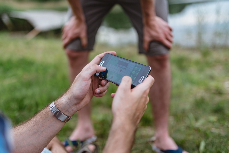 videogame, outdoors, holding, mobile, playing, communication, hand, man, fun, two people, smartphone, touching, adult, hands, focus on foreground, play