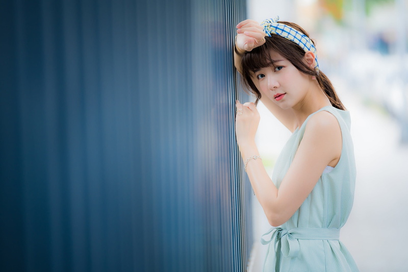 wall - building feature, lifestyles, contemplation, real people, hairstyle, depth of field, beauty, casual clothing, women, looking at camera, dress, beautiful woman