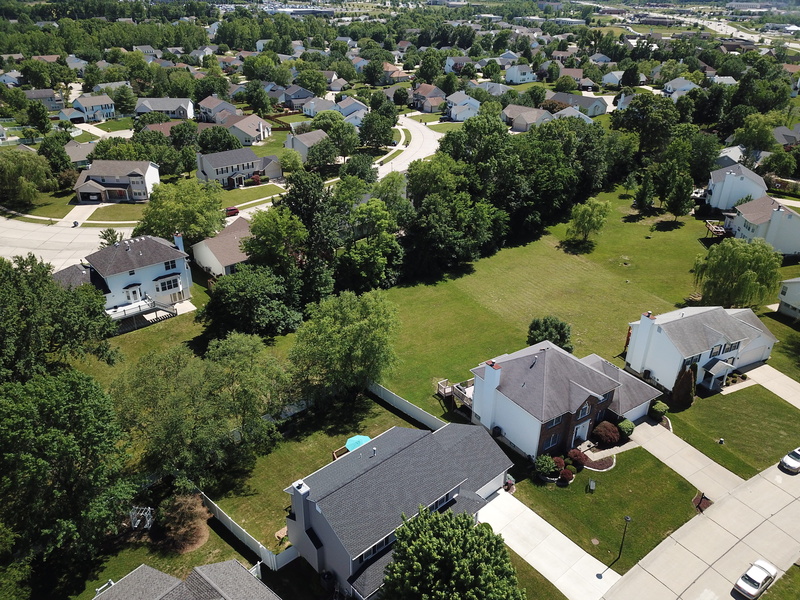 growth, yard, landscape, city, houses, environment, building exterior, green color, house, built structure, vehicles, tree, outdoors, lawn, building, high angle view
