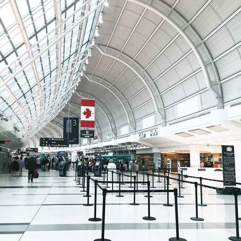 human, table, travel, flooring, incidental people, flag, ceiling, toronto pearson airport, large group of people, walking, transportation, mode of transportation