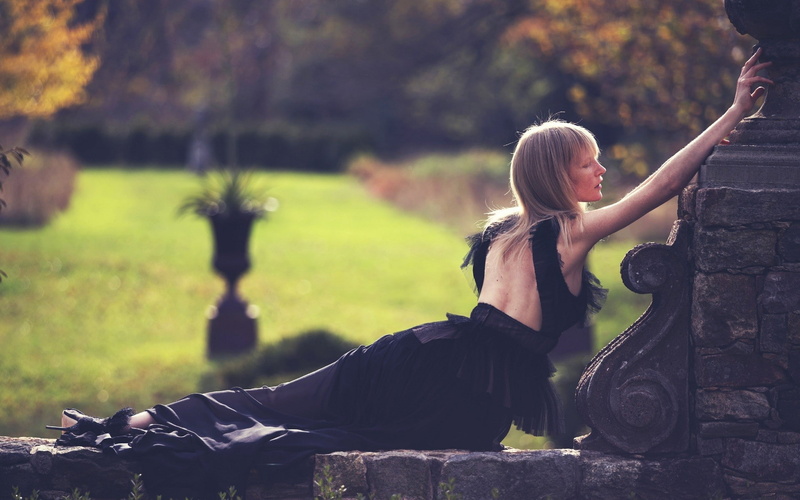 Kirsten Owen, focus on foreground, black dress, hair, 1080P, sitting, lifestyles, real people, hairstyle, full length, sunlight, blond hair, leisure activity