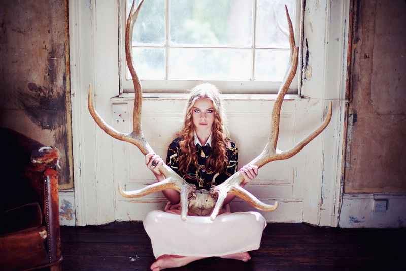 blond hair, blonde, adult, barefoot, real people, leisure activity, horns, hairstyle, antlers, young adult, portrait, front view, emotion, sitting, long hair