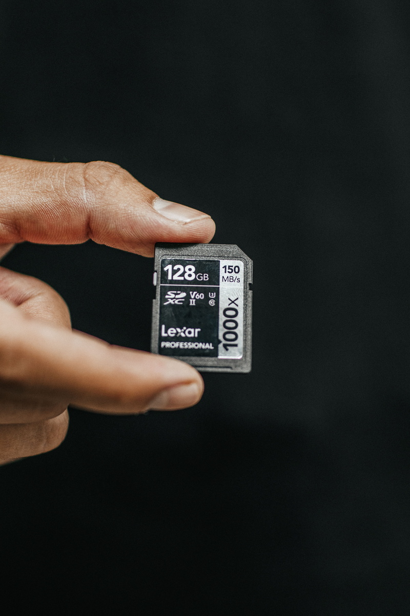 lexar, side view, card, unrecognizable person, dark, copy space, indoors, human body part, sd, push button, black background, finger, message, human, communication