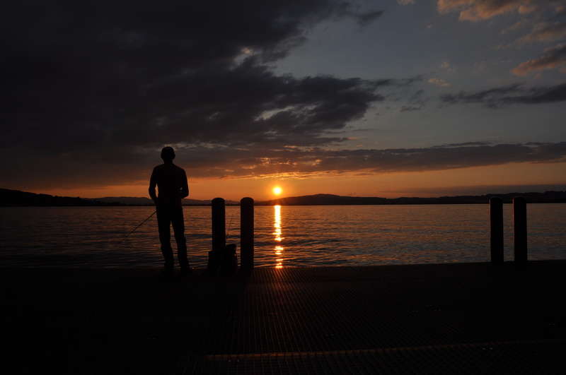 tranquil scene, lifestyles, fishing rod, standing, sky, land, beach, orange color, men, sea, cloud - sky, silhouette, table, beauty in nature, real people