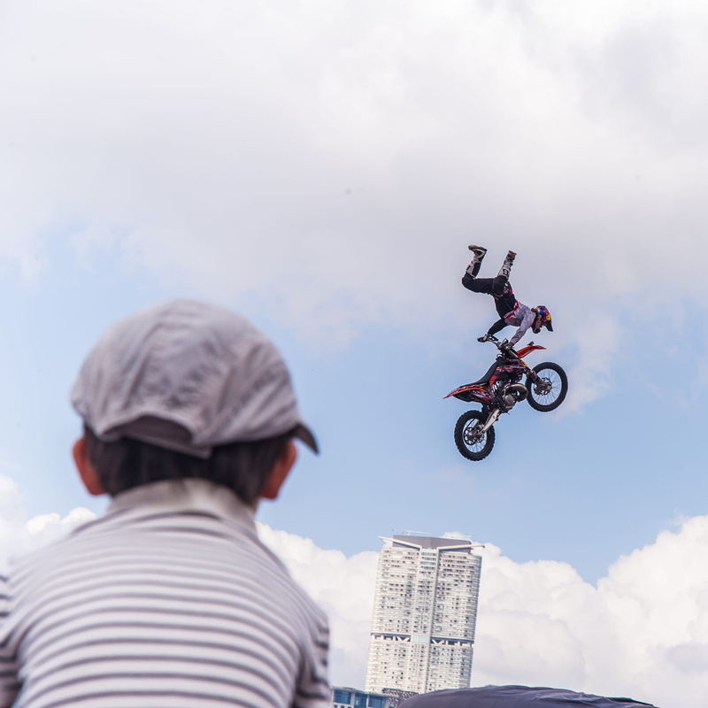 child, sky, people, land vehicle, lifestyles, mid-air, outdoors, skill, cloud - sky, men, leisure activity, redbull, crash helmet, headwear, real people