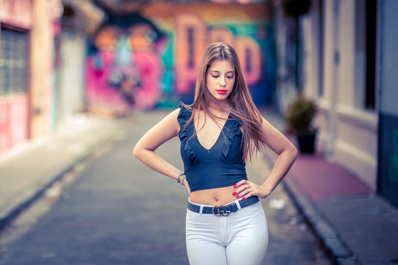 2K, pierced navel, brunette, urban, women, women outdoors, crop top, long hair, red lipstick, hands on hips, painted nails, white  pants, pierced nose