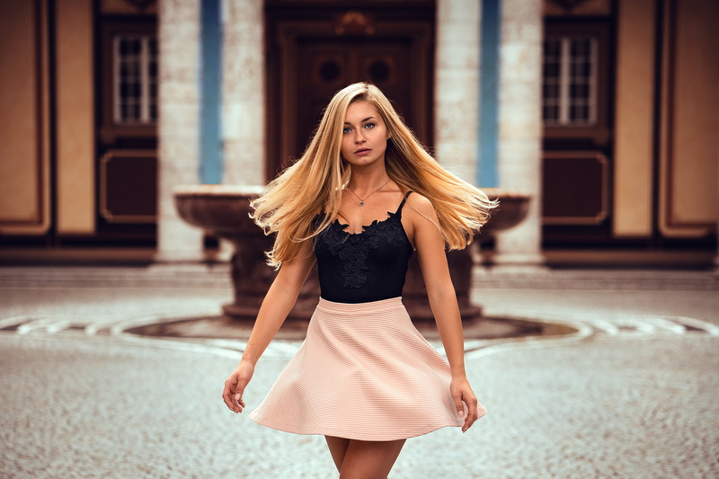 one person, looking at camera, hairstyle, focus on foreground, hair, pink, women, necklace, blonde, pink skirt, black, beautiful woman, three quarter length