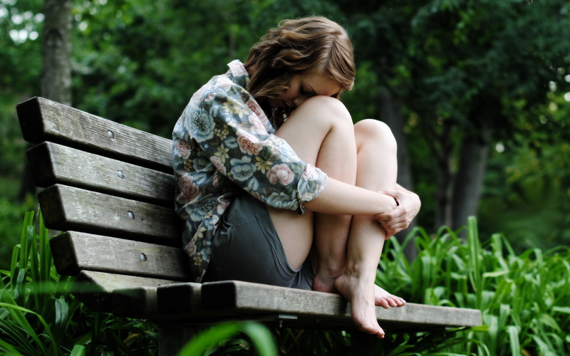outdoors, green color, child, leisure activity, one person, full length, barefoot, tree, day, holding knees, bench, real people, sitting, young adult, blonde