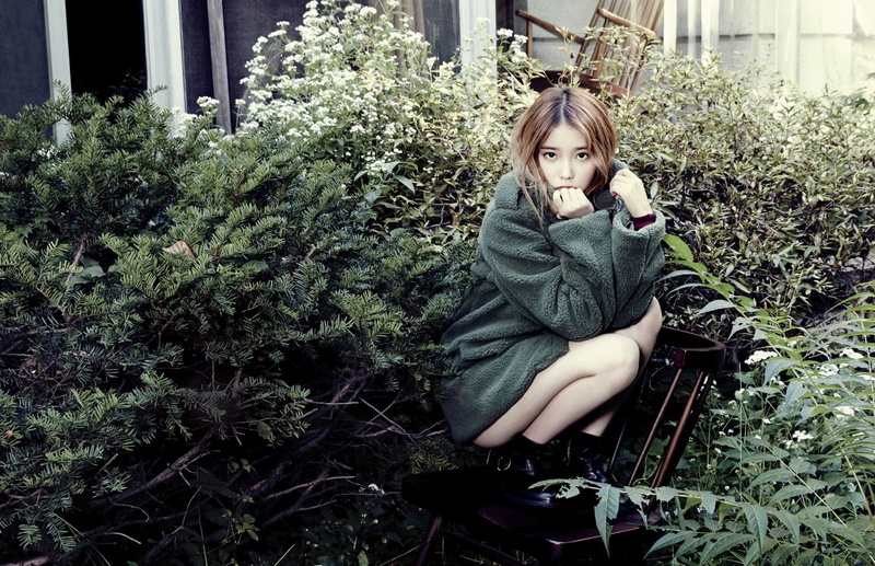 looking at camera, outdoors, green color, women, teenager, beautiful woman, IU, casual clothing, lifestyles, young women, growth, plant, sitting, one person