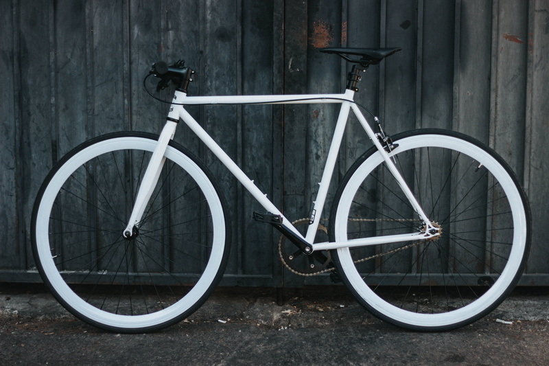 day, building, mode of transportation, transportation, single object, bike, tire, panel, bar, beside, city, stationary, no people, street, built structure