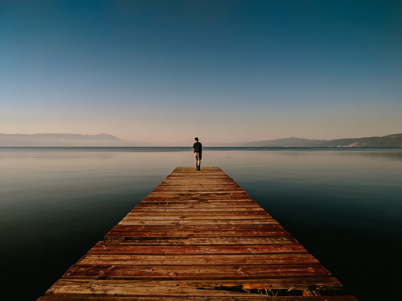 one person, 4K, real people, beauty in nature, coast, scenics - nature, dock, nature, rear view, horizon, tranquility, mountain, boardwalk, shore, standing