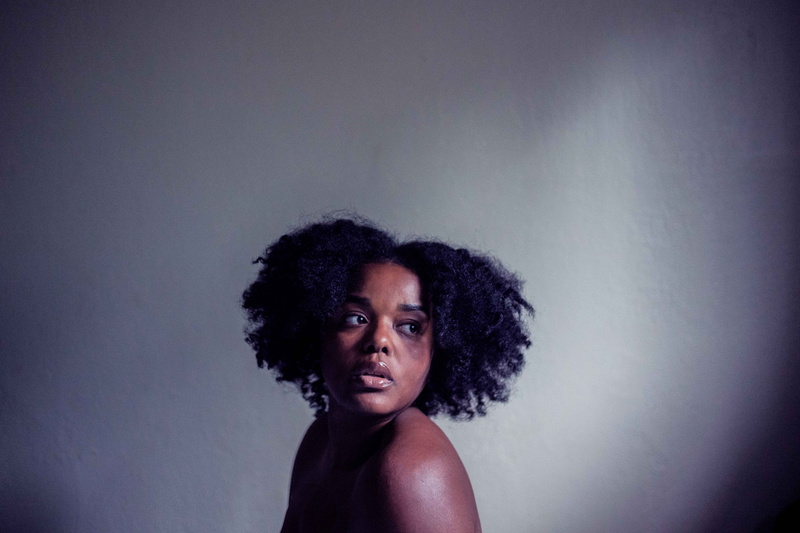 human hair, person, looking at camera, indoors, female, portrait, afro, scared, lonely, sad, headshot, adult, hairstyle, emotion, hair, cold, serious, lady