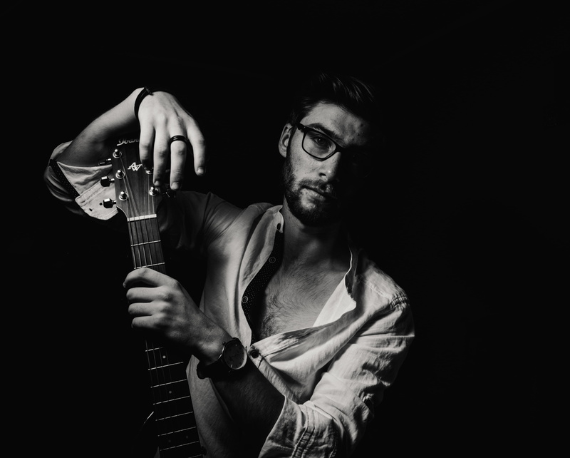 front view, performance, plucking an instrument, musical instrument, musician, charming, grayscale, one person, guitar, indoors, musical equipment, string instrument
