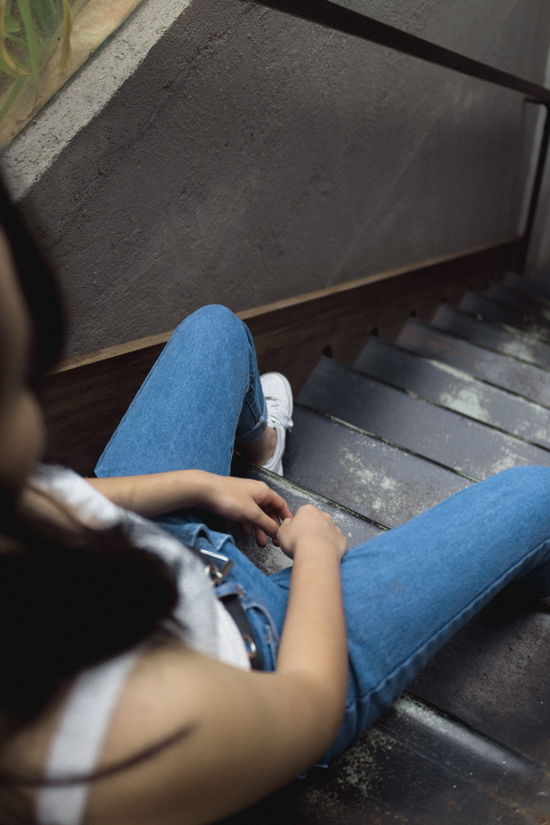 sitting on stairs, ankle, path, asphalt, jeans, real people, lifestyles, stair, low angle, men, blue, clothing, stairs, denim, female, day, gray, sad, waiting