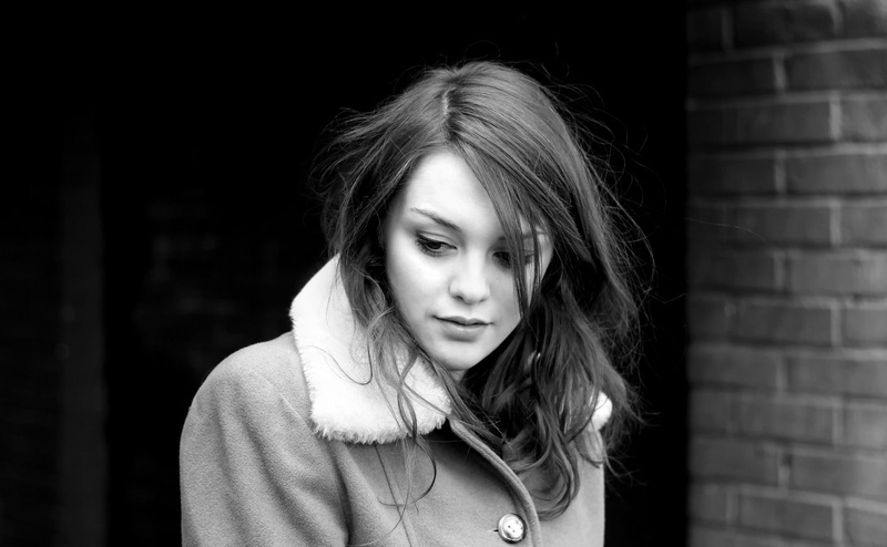 1080P, focus on foreground, portrait, model, brick wall, black background, casual clothing, young adult, looking, beautiful woman, contemplation, teenager
