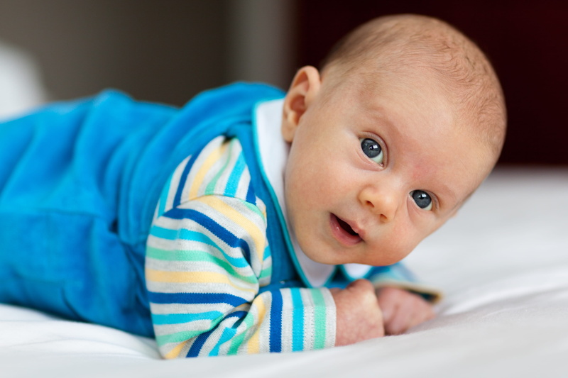 wearing, one person, young, person, baby, footie, blue, look, relaxation, arms, indoors, offspring, bedroom, innocence, looking at camera, lying, belly