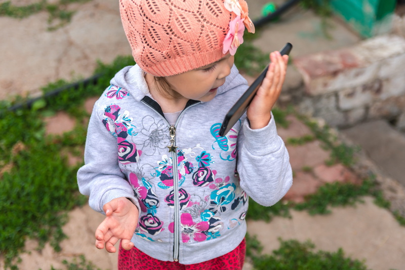 conversation, person, offspring, outdoors, one person, girls, clothing, baby, standing, entertainment, childhood, smart phone, in the summer of, girl, portable information device
