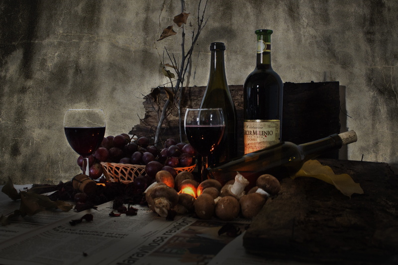 table, food and drink, red wine, wine bottle rack, grape, wine bottle, glasses, i am a student, red, two, surrounded, indoors, no people, three, container