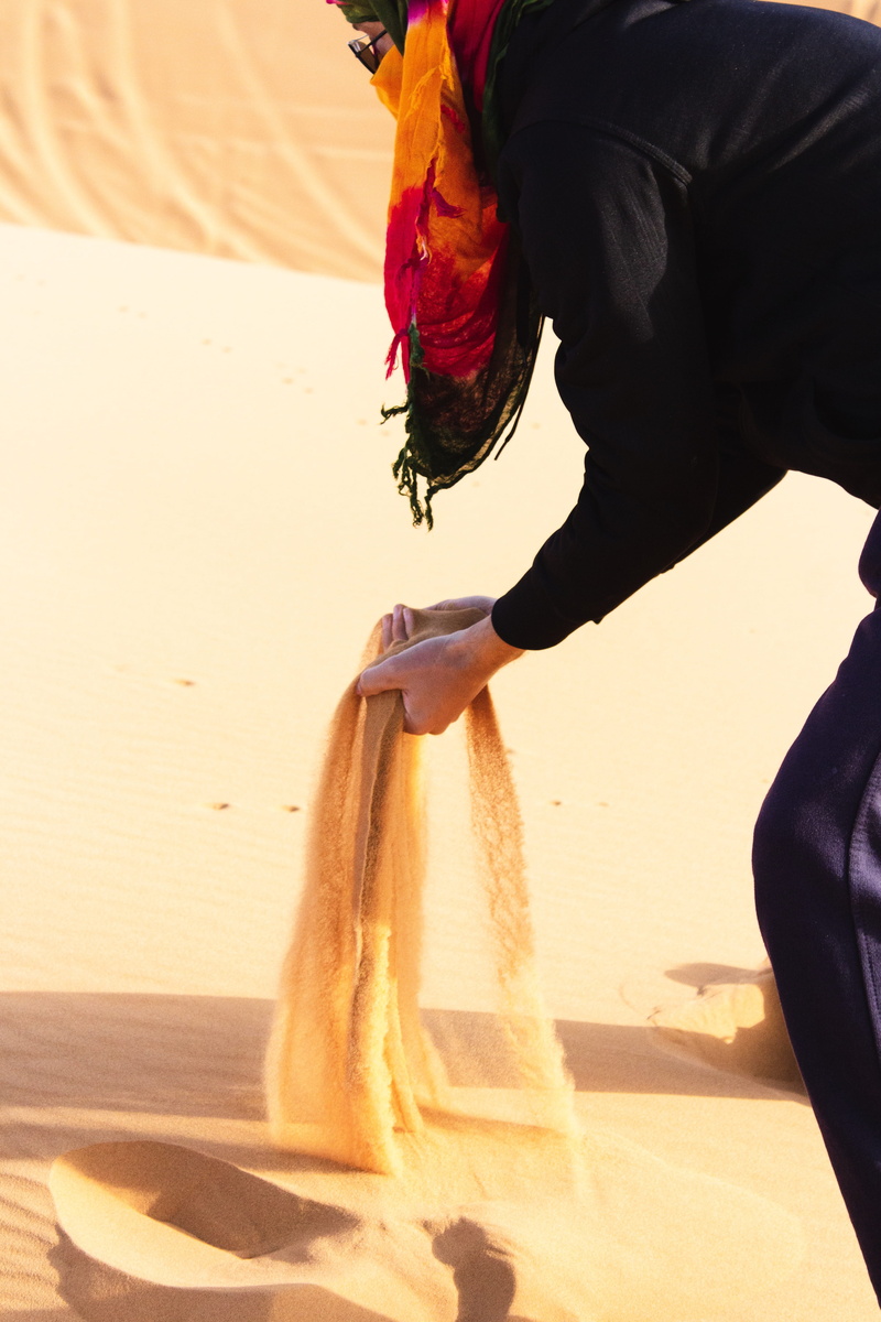 holding, horizon, land, beach, sand, one person, merzouga, water, apparel, wild, outdoors, person, occupation, lifestyles, hand, motion, standing, human body part