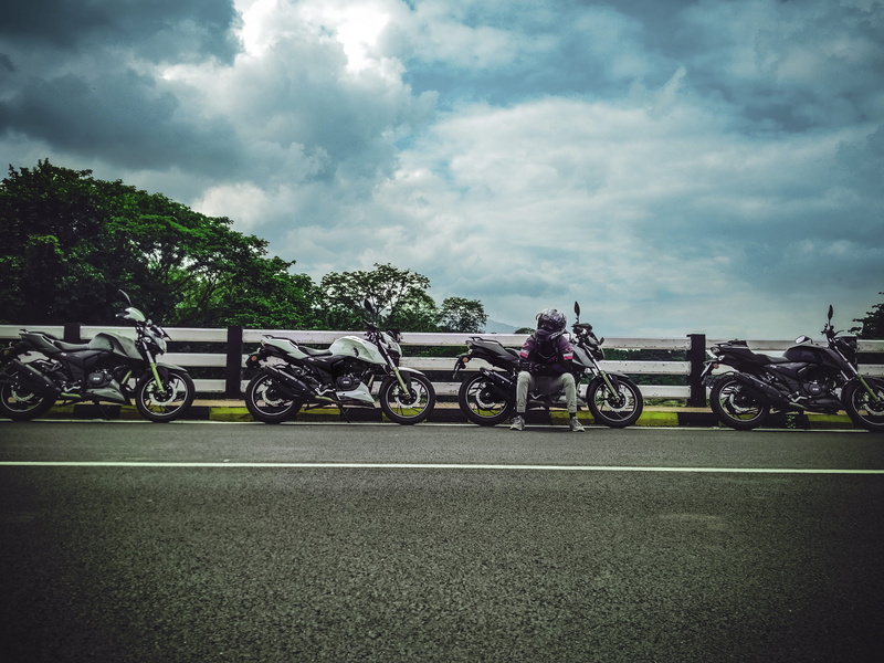 wheel, mode of transportation, plant, street, beside, sky, skies, outdoors, sitting, pavement, motorcycle, hurry, ride, transportation, nature, clouds