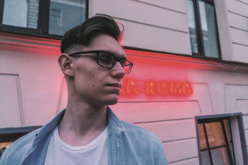 pale, front view, one person, real people, young men, text, day, outdoors, eyeglasses, night, looking, neon, casual clothing, street, glasses, blue, leisure activity