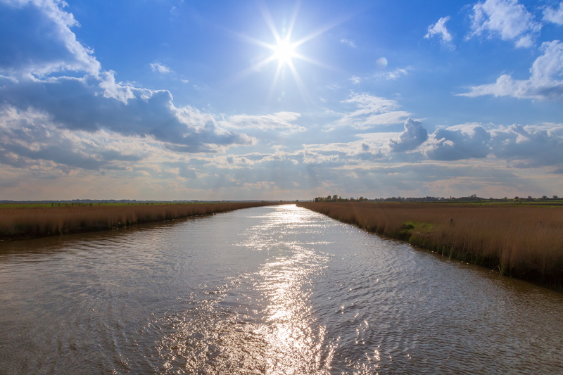lens flare, blue skies, water, bright, land, non-urban scene, norfolk, waterfront, sunlight, idyllic, beauty in nature, sunbeam, nature, canal, united kingdom