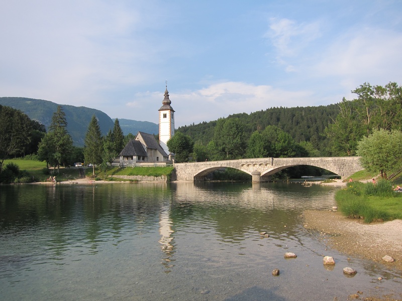 sky, village, river, lake, plant, no people, old town, bohinj lake, building exterior, built structure, krstnika, mountains, water, tree, connection, cloud - sky