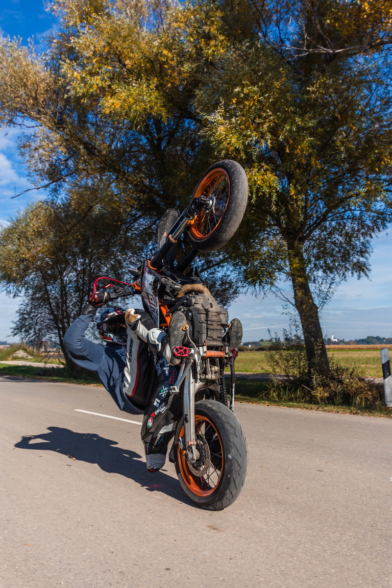 sunlight, dynamic, full length, people, drive, motorcycle, road, mode of transportation, summer, city, stunt, landscape, sky, tree, transportation, riding