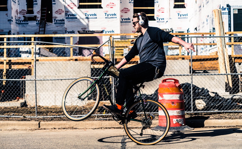 near, chain, transportation, railing, built structure, fence, land vehicle, 1080P, adult, riding, one person, outdoors, headphone, cycle, 10 speed, architecture