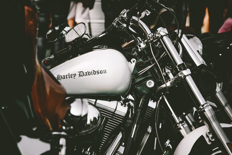 human body part, handle, headlights, metal, harley davidson, parked, city, metallic, headlight, incidental people, cruiser, exhibition, blur, motorcycle