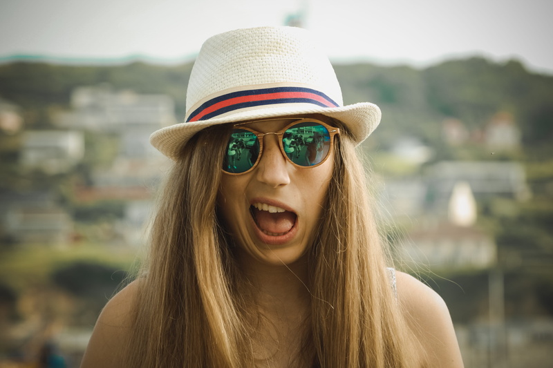 one person, lifestyles, young adult, front view, beautiful woman, focus on foreground, mouth open, day, outdoors, grimace, glasses, hat, hairstyle, summer