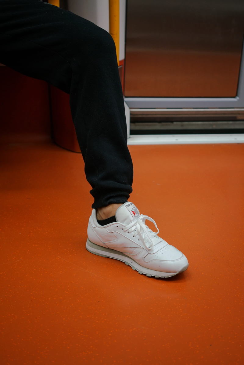 sneaker, flooring, indoors, home interior, human foot, human limb, sitting, human body part, white, brown, shoe, casual clothing, unpaired, day, standing