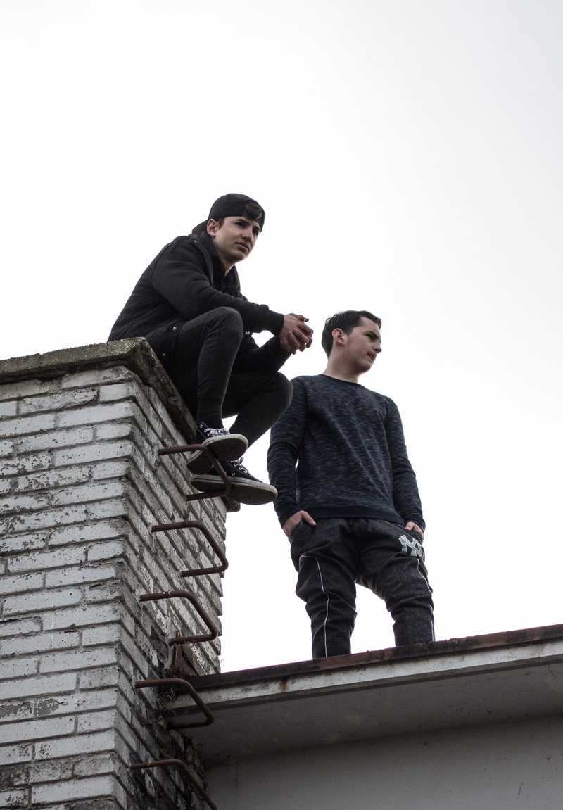 2K, sweatshirt, casual clothing, building exterior, hight, leisure activity, built structure, day, outdoors, chimeney, two people, rooftop, standing, architecture