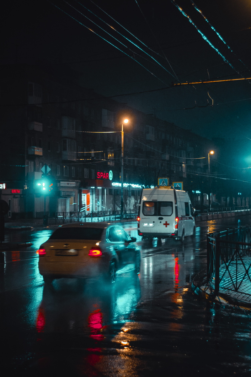 city street, car, street, built structure, no people, lights, illuminated, dark, lampposts, night time, rain, land vehicle, urban, travelling, water, rainy season