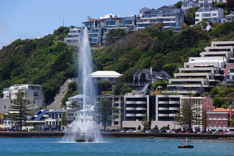 waterfront, fountain, incidental people, sea, motion, building exterior, tourism, architecture, outdoors, splashing, 5K, city, harbor, cityscape, plant