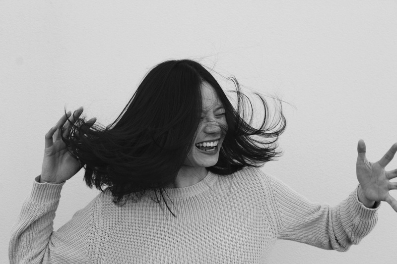 flicking, women, warm clothing, front view, happiness, 2K, waist up, emotion, real people, human arm, grayscale, young adult, one person, casual clothing