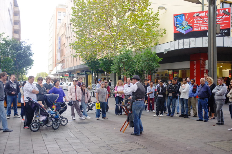 city street, land vehicle, women, mall, day, south australia, city life, men, group of people, plant, illusionist, real people, large group of people, magician