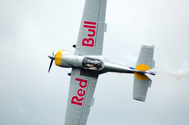 red bull, air vehicle, outdoors, text, 2K, transportation, red, airplane, nature, no people, security, sky, gray, mid, built structure, air, bull, safety
