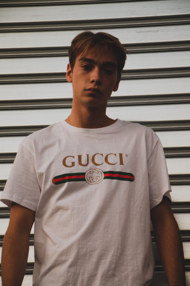 portrait, looking at camera, man, text, parisian, white, serious, shirt, lifestyles, western script, adolescence, standing, young men, sneaker, streetwear