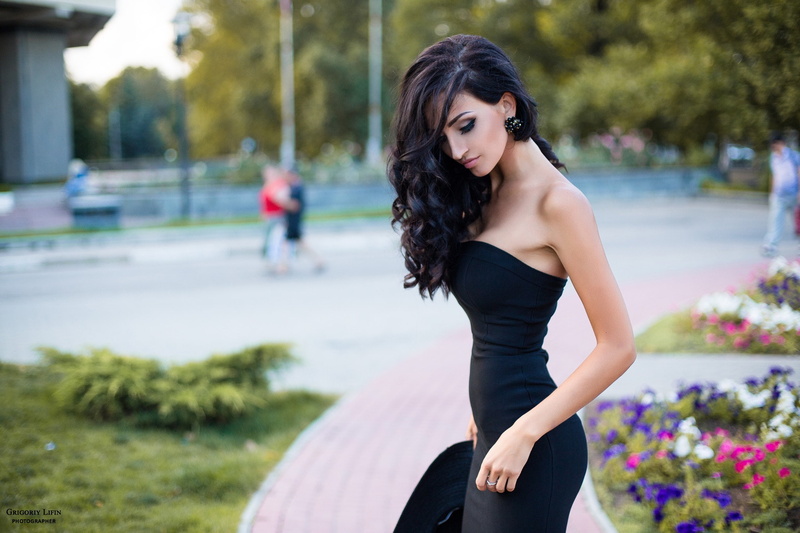 brunette, one person, black dress, women outdoors, fashion, wavy hair, hair, plant, dress, focus on foreground, beautiful woman, classy, leisure activity