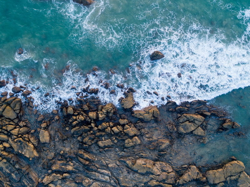 high angle view, no people, shore, sea, blue, rocks, outdoors, wave, land, flowing water, rocky coastline, rock, sport, day, rock - object, brown, turquoise