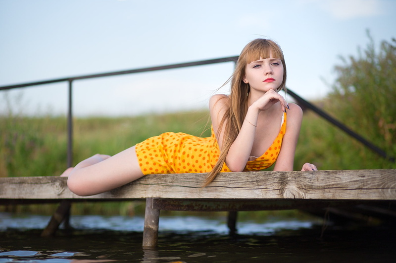 model, blonde, 720P, yellow dress, outdoors, bokeh, barefoot, bare shoulders, lying on front, women outdoors, women, dress, looking at viewer, water