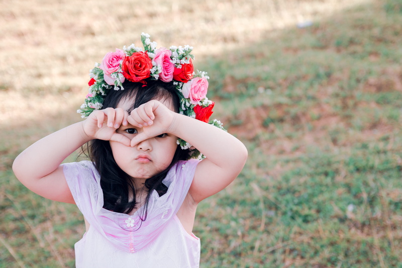 women, front view, hand, real people, facial expression, face, little, innocence, person, plant, child, beautiful, outdoors, focus on foreground, flower