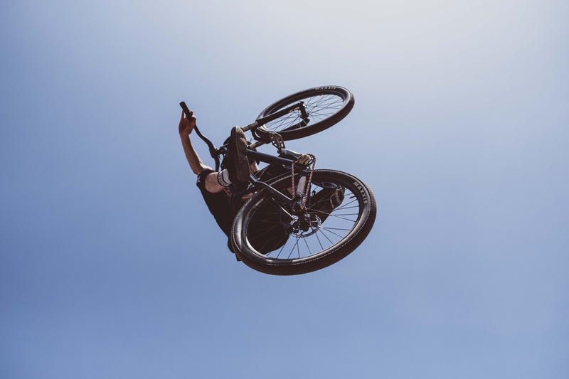 bike, person, brick, activity, wheel, clear sky, vehicle, low angle view, blue, adventure, housing, black, cycling, mountain biking, spoke, leisure activity